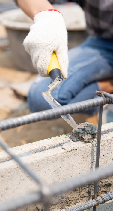 Bricklayer worker installing brick masonry on exterior wall with trowel putty knife