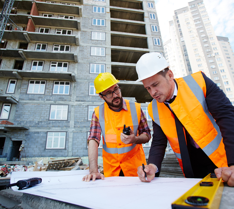 Modern engineer pointing at sketch in blueprint while explaining it to colleague
